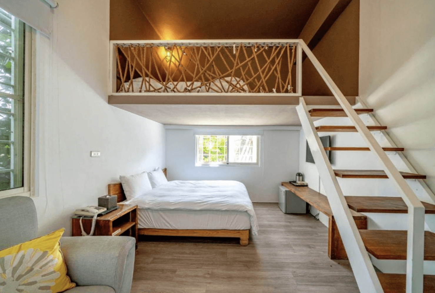 【東華大學民宿】「雲上太陽民宿」樓中樓雙人房，木質地板與白色牆面營造自然簡約風格，設有閣樓床位與溫馨窗景，空間寬敞明亮、氛圍放鬆。