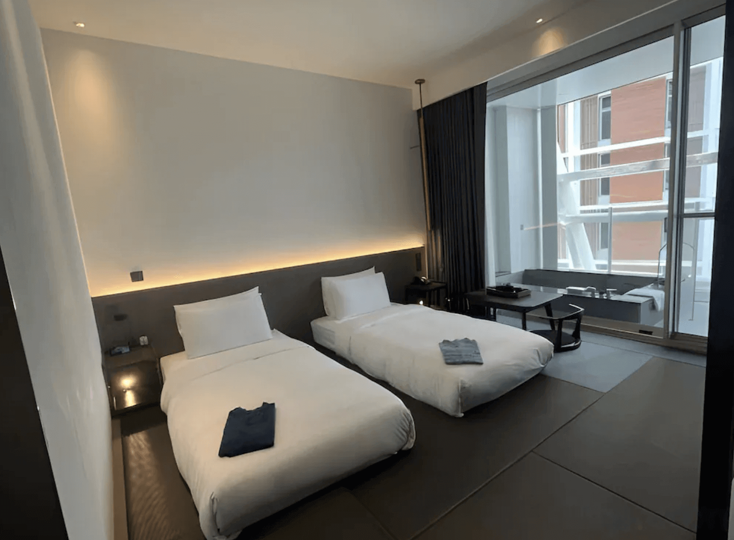 【宜蘭溫泉飯店】「風華渡假酒店・礁溪館日式風格雙床房，榻榻米地板搭配極簡床鋪與柔和燈光設計，房內設有落地窗與和式桌椅，空間靜謐舒適。」