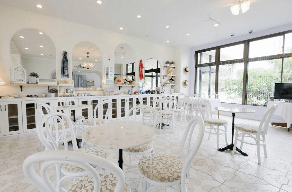 【奄美大島住宿】「龍美 Caretta 飯店（Hotel Caretta Amami）的餐廳空間，採白色田園風格設計，搭配圓桌與花紋椅子，採光明亮、氛圍典雅。」