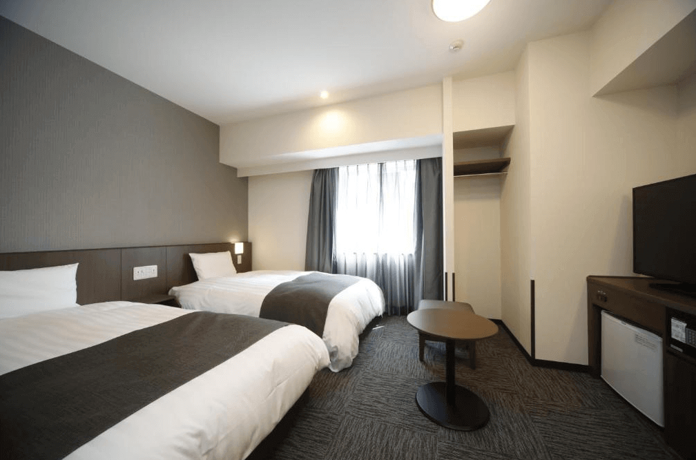 【大分住宿】Dormy Inn大分自然溫泉 (Dormy Inn Oita Natural Hot Springs) 的雙床客房,設計採用溫暖的米色與深木色調,設有可將寢室與玄關走道區隔開來的拉門,確保旅客享有安靜私密的睡眠環境。