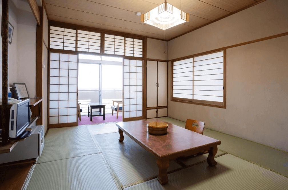 【屋久島住宿】「Hotel Yakushima Sanso 傳統和式榻榻米客房，配置矮桌與坐墊，採光良好，並可通向附設陽台的休息區。」