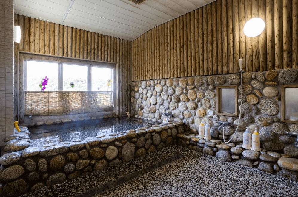 【屋久島住宿】「Hotel Yakushima Sanso 室內岩石風溫泉浴場，採用大面積石牆與木質設計，池水熱騰騰冒著蒸氣，營造自然放鬆的泡湯氛圍。」