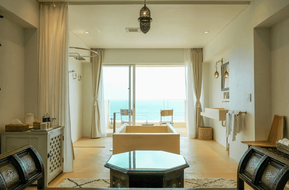【沖繩南城住宿】Riad Lamp 的海景衛浴空間，房內正中央設有一座大型獨立浴缸，上方懸掛著精緻的摩洛哥吊燈，旅客可透過落地窗欣賞蔚藍海平線，享受極致放鬆的泡澡時光。