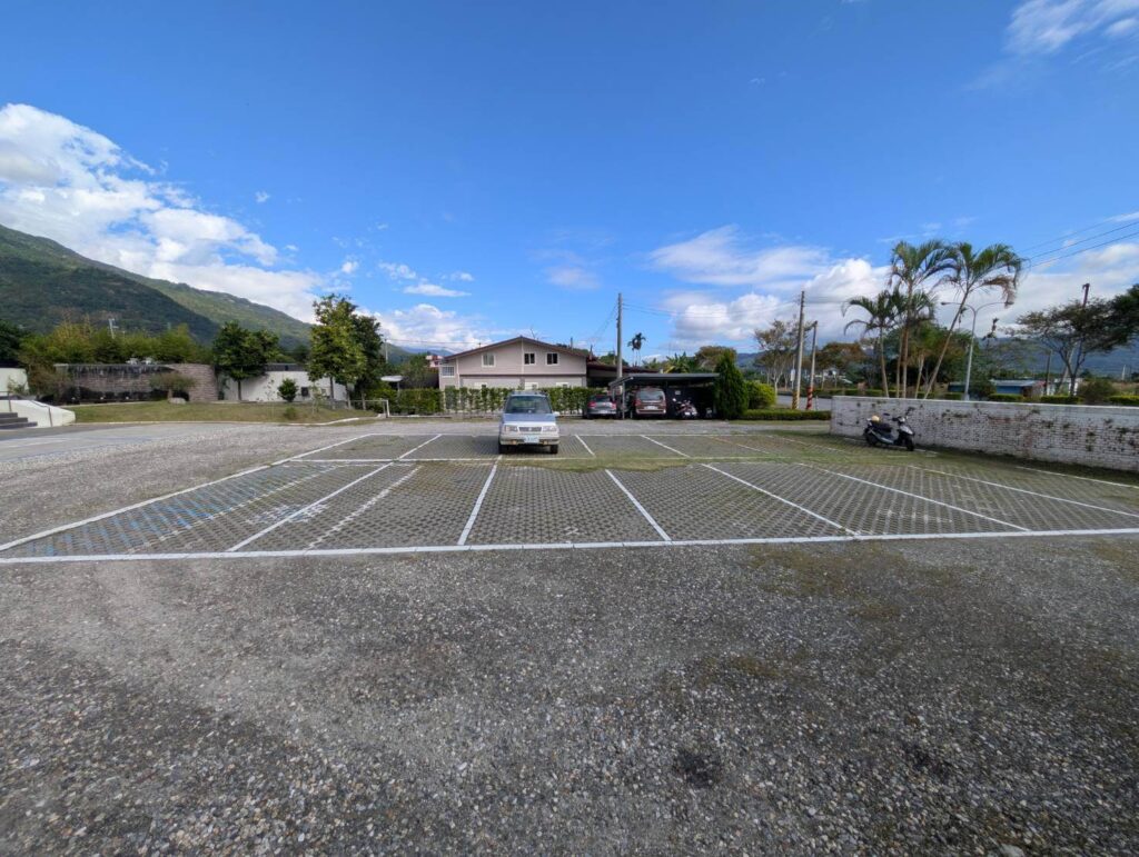 【元湯溫泉居住宿】「花蓮《元湯溫泉居》戶外停車場：寬敞平整的地面停車區，四周被山景與綠意包圍，提供旅客便利且舒適的停車空間。」