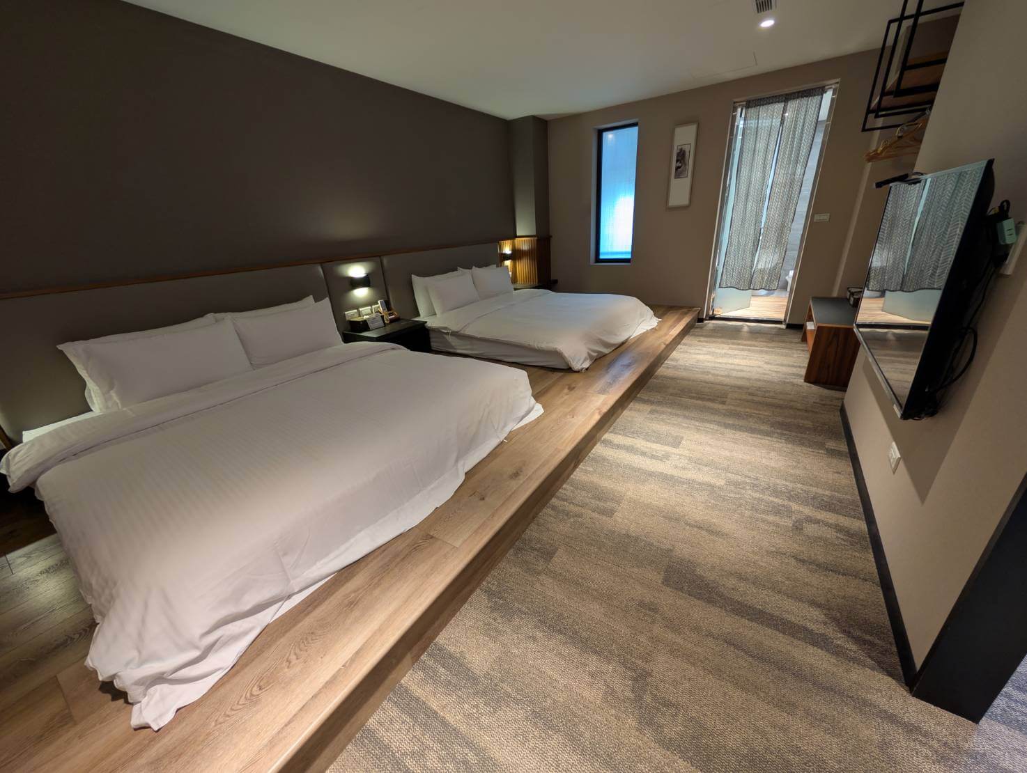 〈元湯溫泉居〉和式四人房內景，設有兩張加大雙人床，房間採用抬高木質地板與柔和燈光設計，空間寬敞舒適並附設電視與落地窗。