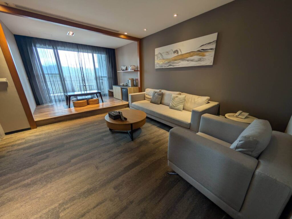 〈元湯溫泉居〉和式四人房的客廳區，擺設舒適的沙發與茶几，並配有大面落地窗採光。