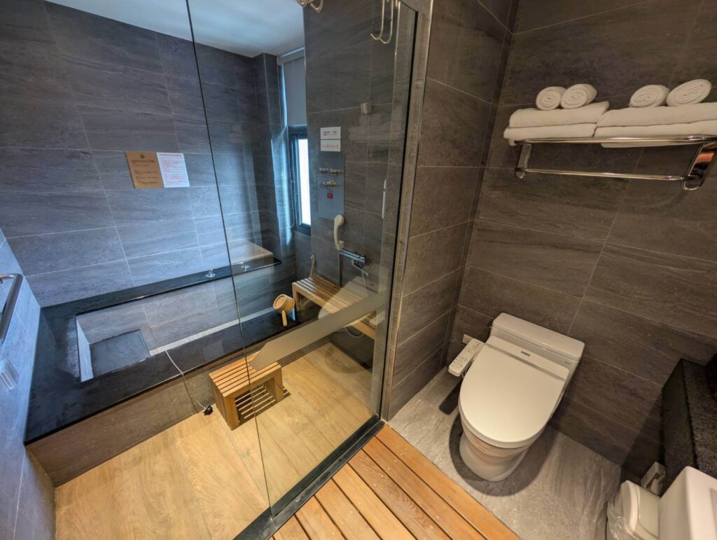 〈元湯溫泉居〉和式四人房的私人泡湯空間，採用大面積石材與木質地板，設有淋浴區及深型浴池。