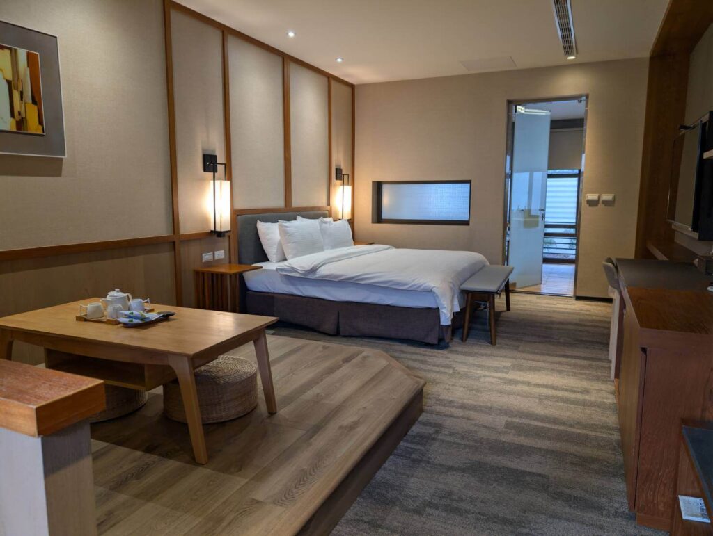 〈元湯溫泉居〉和式雙人房，搭配簡約木質牆板設計，內附舒適大床與低矮茶几區。