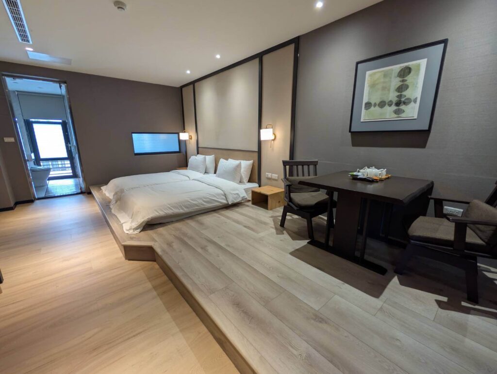 〈元湯溫泉居〉洋式雙人房，設有和風抬高地板、雙人床與一組和式小餐桌，空間寬敞且富日式禪意。
