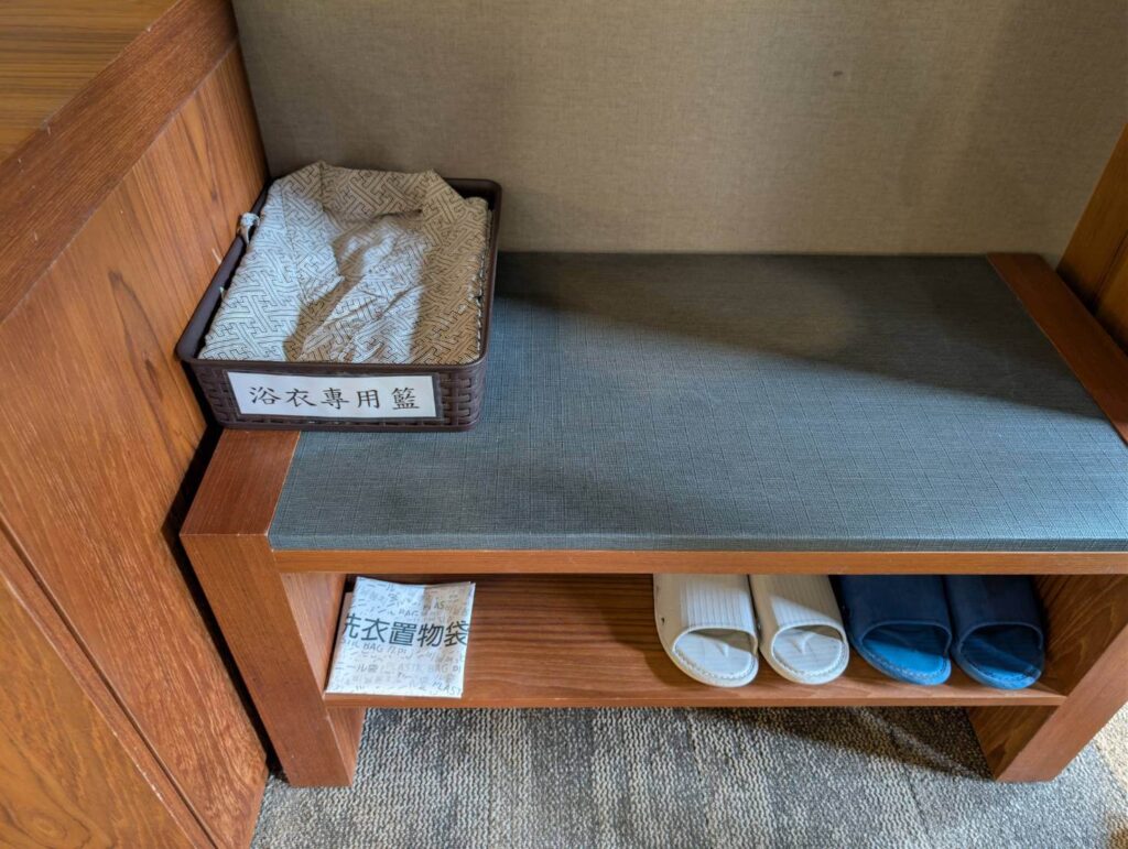 〈元湯溫泉居〉提供浴衣專用籃、備品置物袋與室內拖鞋，整齊收納於木質櫃體中。