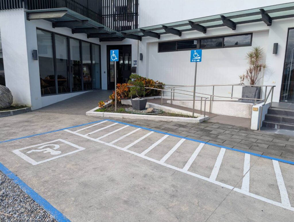 【元湯溫泉居住宿】「花蓮《元湯溫泉居》館前無障礙設施：包含劃設清楚的無障礙停車位、平緩的無障礙坡道與扶手設計，方便輪椅與行動不便旅客安全出入館內。」