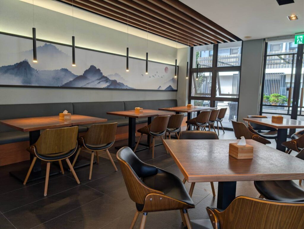 〈元湯溫泉居〉餐廳用餐環境，設有大片山水風格壁畫、木質桌椅與柔和燈光，營造舒適典雅的用餐氣氛。