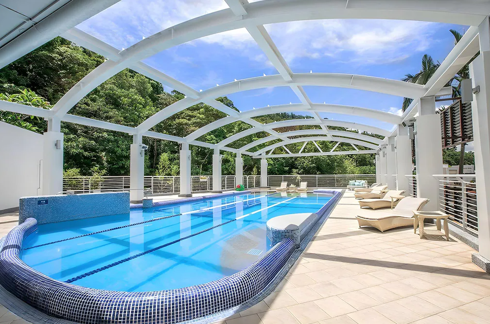 北投大地酒店 (The Gaia Hotel) 的戶外泳池區域，上方設有獨特的白色造型遮棚，在藍天與周圍翠綠山林的映襯下，提供旅客舒適自在的戲水空間。