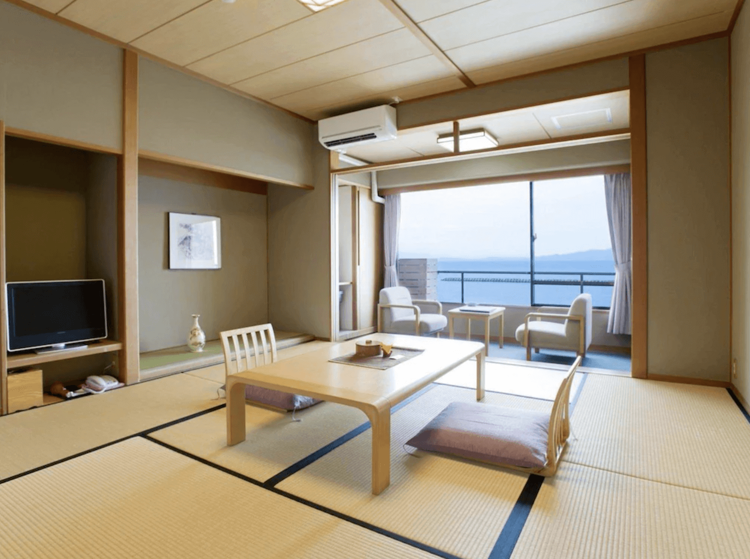 【指宿住宿】吟松花之溫泉飯店 (Hana no Onsen Hotel Ginsyo) 的海景和室客房，擁有傳統榻榻米空間與日式矮桌，落地窗邊設有專屬休憩區，讓旅客能悠閒地眺望錦江灣的寧靜海景。