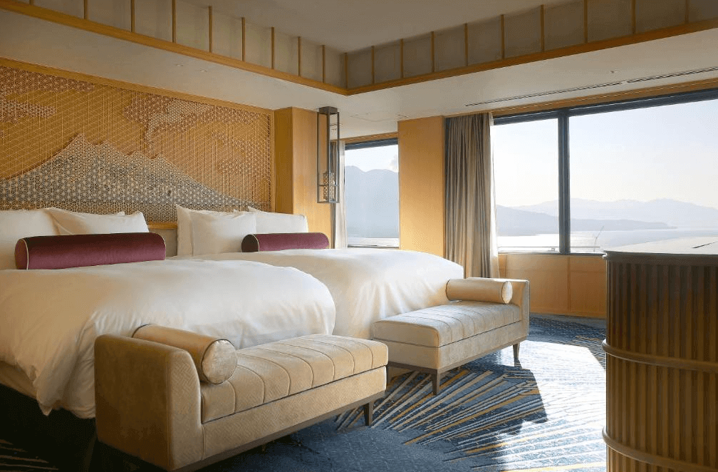 【鹿兒島住宿】城山觀光飯店 (SHIROYAMA HOTEL kagoshima) 融合日式傳統工藝的豪華客房，床頭飾有精緻的木格柵設計，落地窗外正對著壯麗的櫻島火山與錦江灣海景。