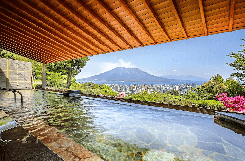 【鹿兒島住宿】"櫻島住宿精選示意圖"城山觀光飯店 (SHIROYAMA HOTEL kagoshima) 著名的露天溫泉「薩摩之湯」，旅客可在此邊享受天然溫泉，邊眺望前方雄偉的櫻島火山與鹿兒島市街全景。