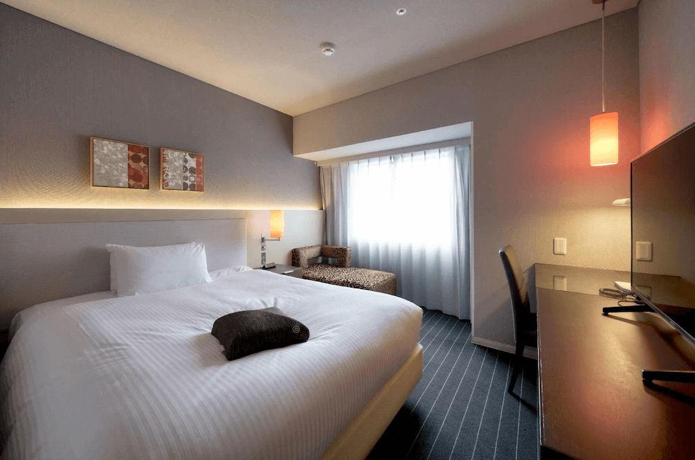 【大分住宿】大分Forza飯店 (Hotel Forza Oita) 的時尚雙人客房,設計風格現代沉穩,房內配有一張舒適的大床,窗邊特別設置了獨特的豹紋休閒躺椅與長條形辦公桌,兼顧商務與休憩需求。