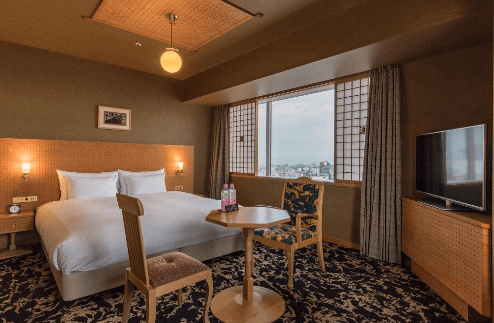 【大分住宿】大分JR九州布魯斯姆酒店 (JR Kyushu Hotel Blossom Oita) 的高級雙床客房,採用和洋融合的設計風格,配有傳統障子窗與溫潤的木質傢俱,窗邊設有休憩桌椅,讓旅客能輕鬆俯瞰大分市區的開闊景致。
