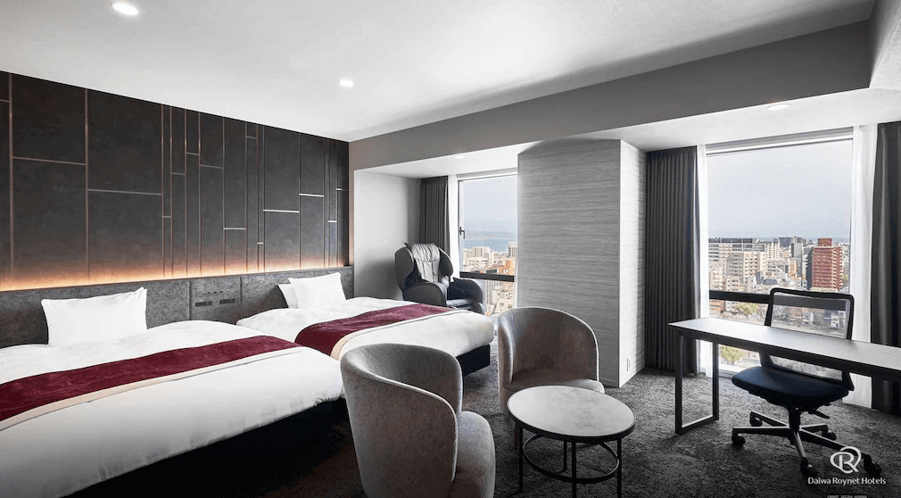 【鹿兒島住宿】大和魯內酒店鹿兒島天文館PREMIER (Daiwa Roynet Hotel Kagoshima Tenmonkan PREMIER) 的景觀雙床客房，房內設計現代時尚，配備深色質感牆面、寬敞的辦公桌區以及一台高級按摩椅，讓商務與休閒旅客都能徹底放鬆。