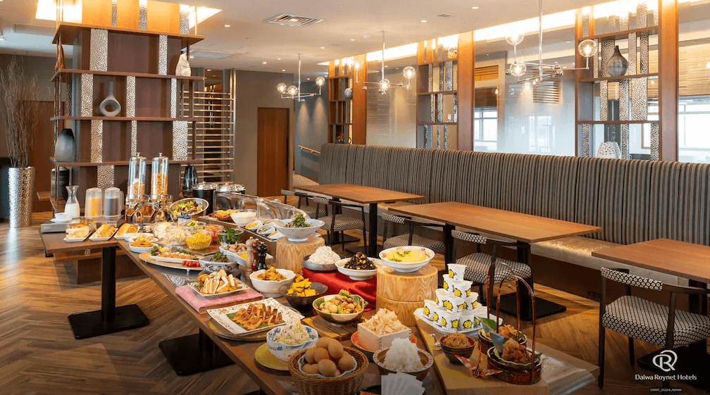 【鹿兒島住宿】大和魯內酒店鹿兒島天文館PREMIER (Daiwa Roynet Hotel Kagoshima Tenmonkan PREMIER) 的自助早餐餐廳，木質調的空間陳設典雅，餐檯上擺滿了豐富多樣的日式與西式料理，提供旅客精緻的早晨饗宴。