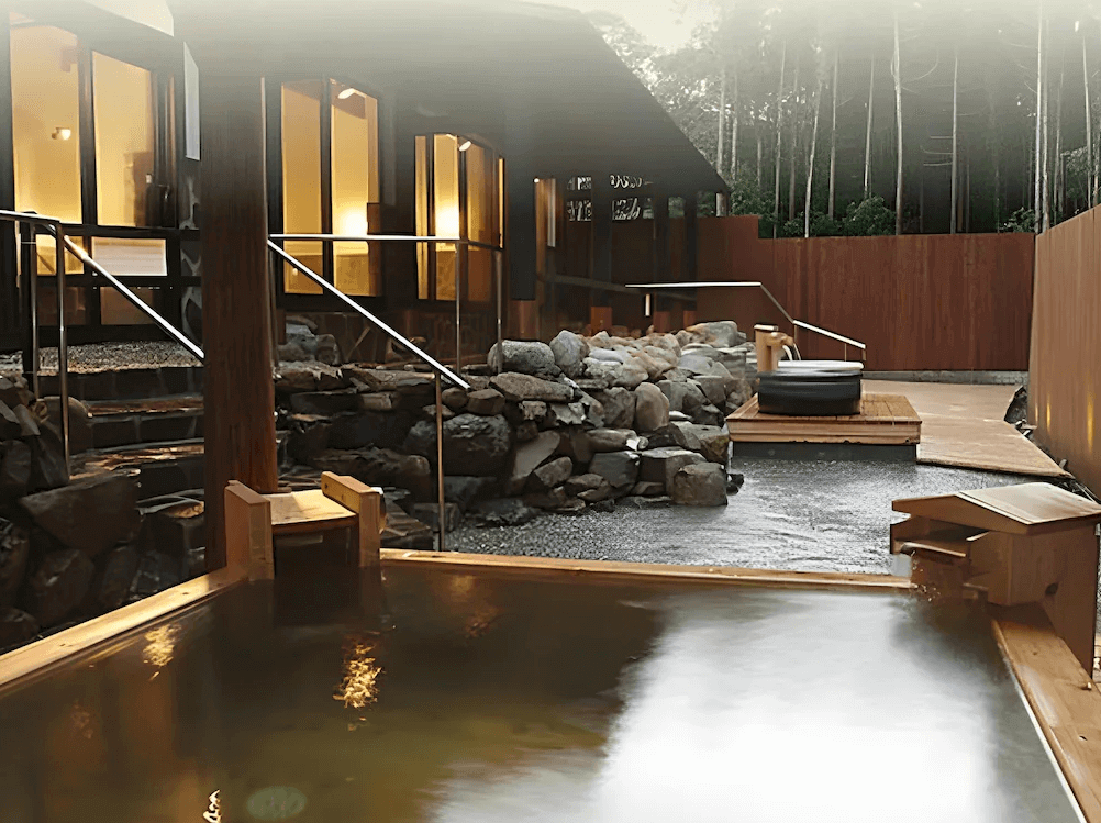 【屋久島住宿】「屋久島Manten旅館（Yakushima Manten Ryokan）露天溫泉區，以岩石與木質材質打造，周圍環繞自然樹林，提供靜謐放鬆的泡湯體驗。」