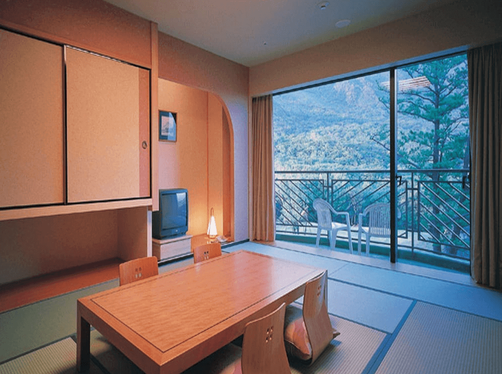 【屋久島住宿】「屋久島岩崎飯店（Yakushima Iwasaki Hotel）和室房型，榻榻米地板與低矮木桌搭配大片落地窗，可欣賞屋久島山景。」