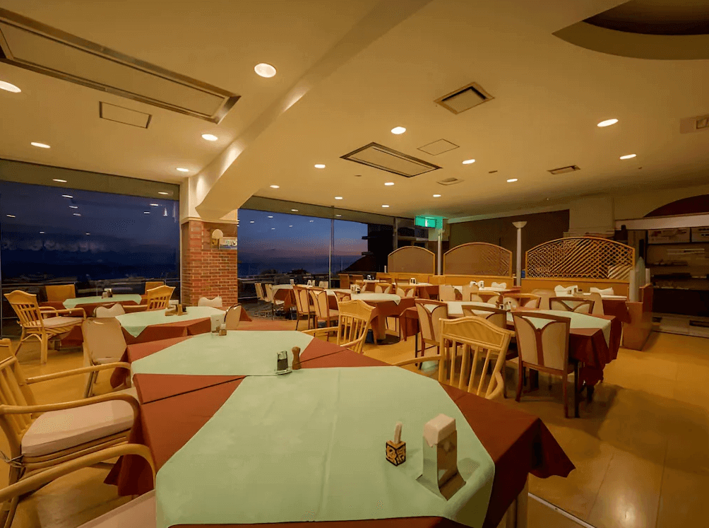 【屋久島住宿】「屋久島海洋與森林飯店（THE HOTEL YAKUSHIMA ocean & forest）館內餐廳，採用溫暖燈光與大面玻璃窗，可在夕陽景色中享用餐點，空間明亮寬敞。」