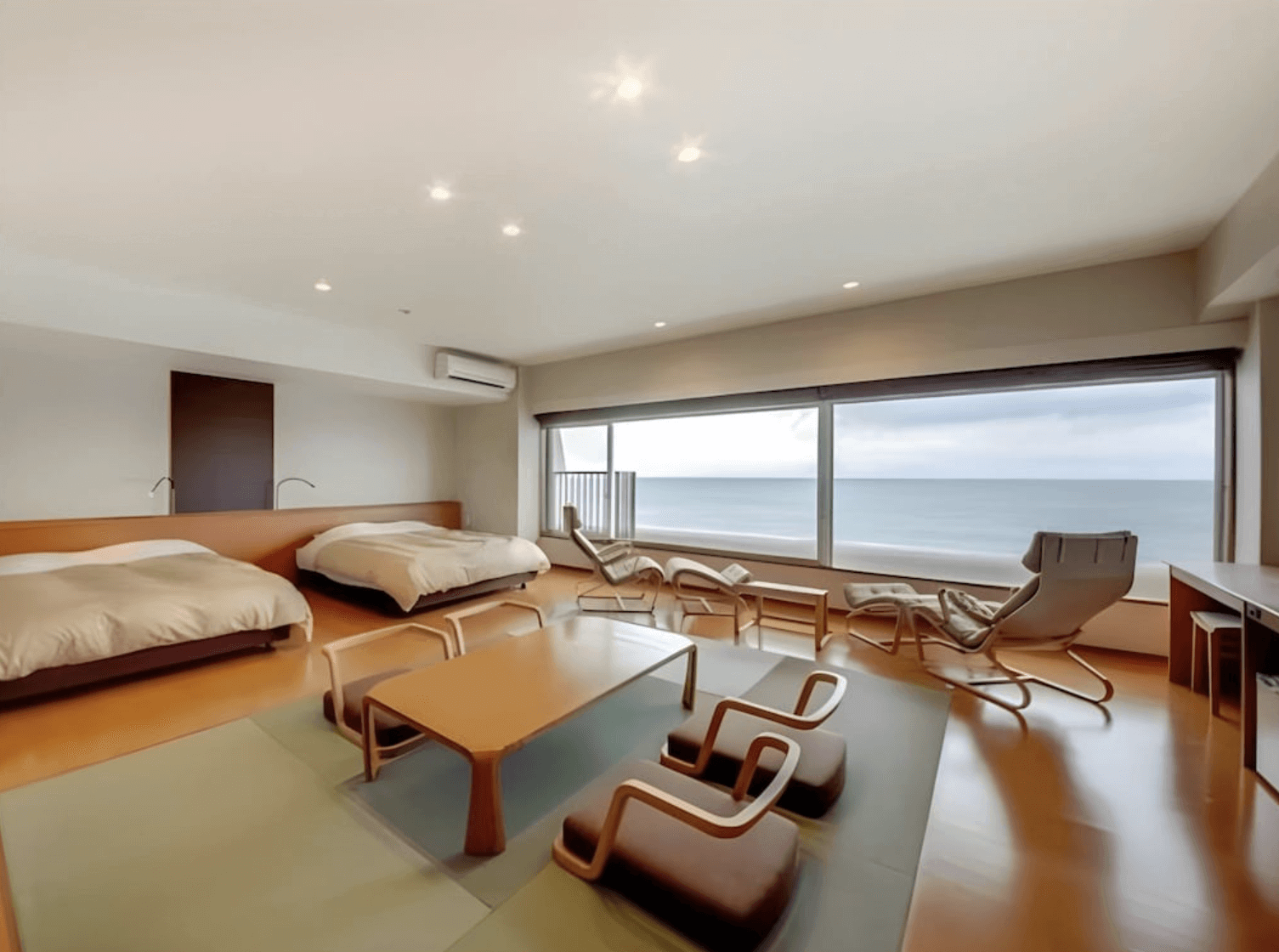 【指宿住宿】指宿休暇村 (Kyukamura Ibusuki) 的寬敞和洋式客房，空間極為開闊，除了舒適的西式床鋪與中央榻榻米座席區外，最令人驚豔的是面海的整面廣角落地窗，窗邊更貼心配置了休閒躺椅供旅客看海發呆。