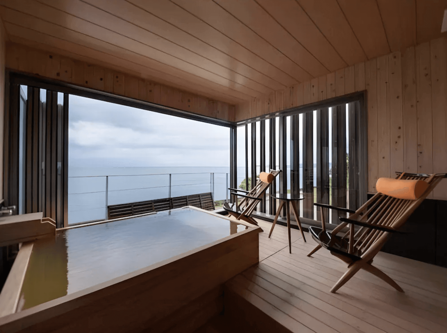 【指宿住宿】指宿休暇村 (Kyukamura Ibusuki) 的半露天溫泉浴池，採用溫潤的木質打造方形浴槽與露台空間，配有兩張舒適的涼椅，讓旅客能一邊享受私密的泡湯時光，一邊感受海風吹拂與無敵海景。