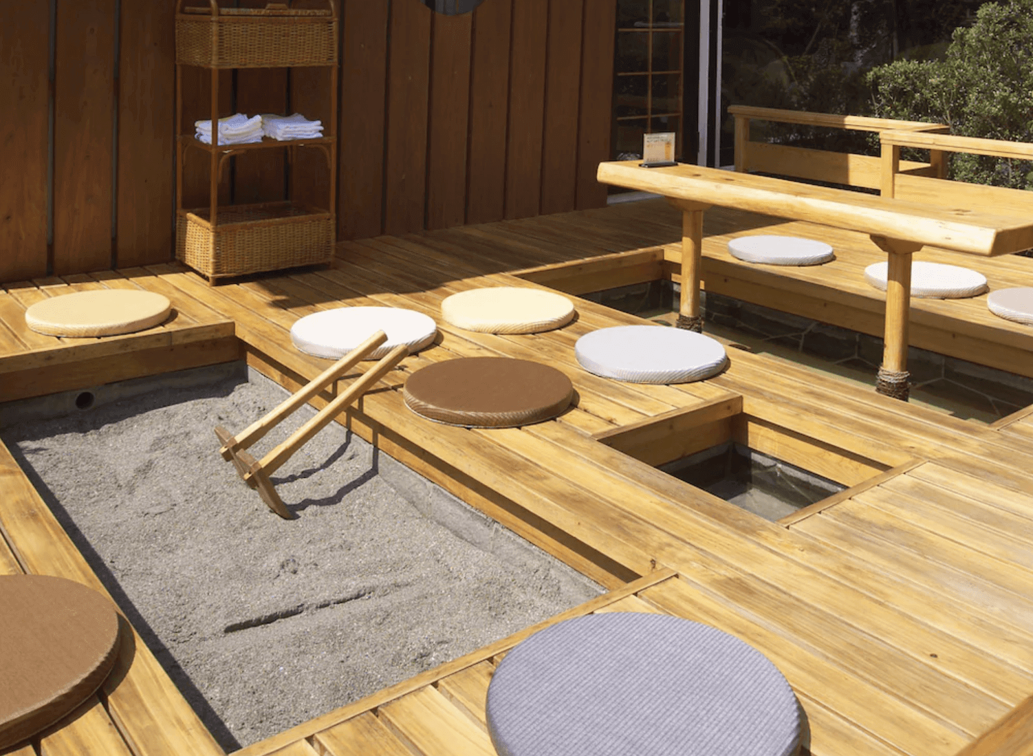 【指宿住宿】指宿秀水園旅館 (Ryokan Ibusuki Syusuien) 的戶外足湯休憩區，鋪設溫潤的木質地板與舒適坐墊，並特別設有迷你的砂蒸溫泉體驗槽，讓旅客輕鬆體驗指宿著名的溫泉特色。