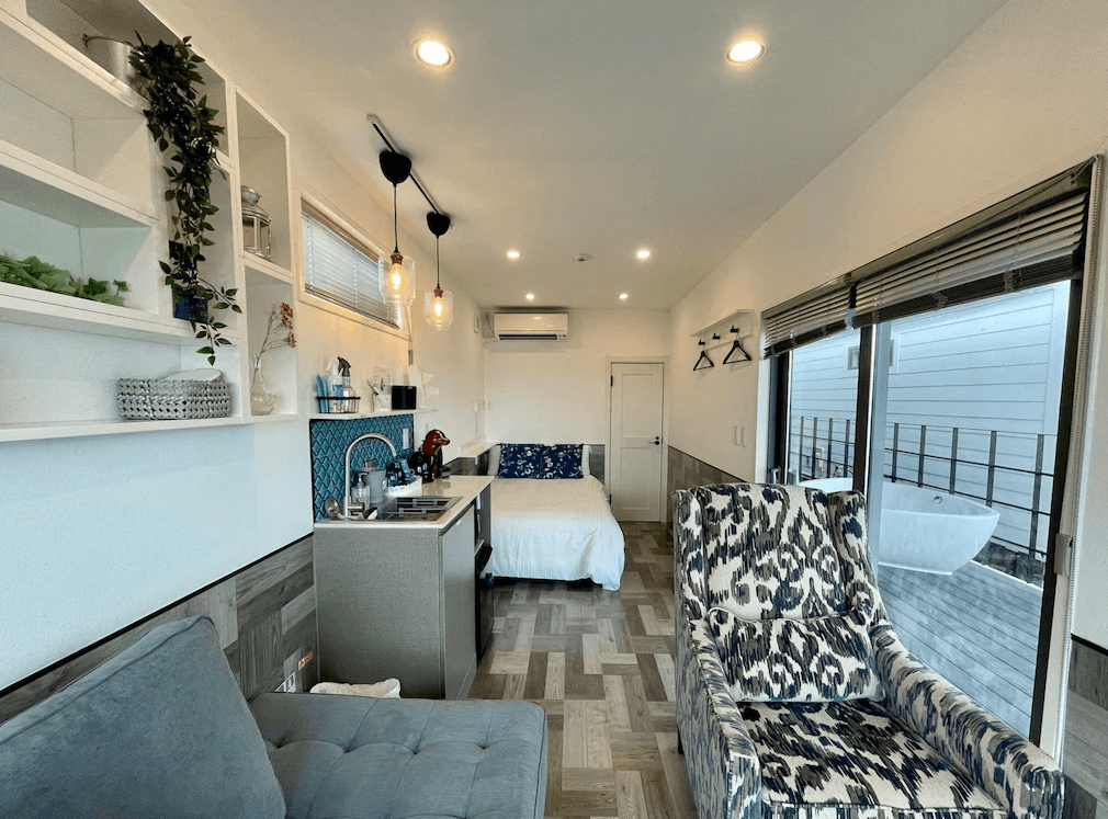 【沖繩南城住宿】榮耀島沖繩藪宿度假村 (Glory island okinawa Yabusachi Resort) 的獨立露營車風格客房，內裝設計精緻現代，設有迷你廚房、舒適沙發與臥床，透過落地窗可直接通往設有露天浴缸的專屬露台。