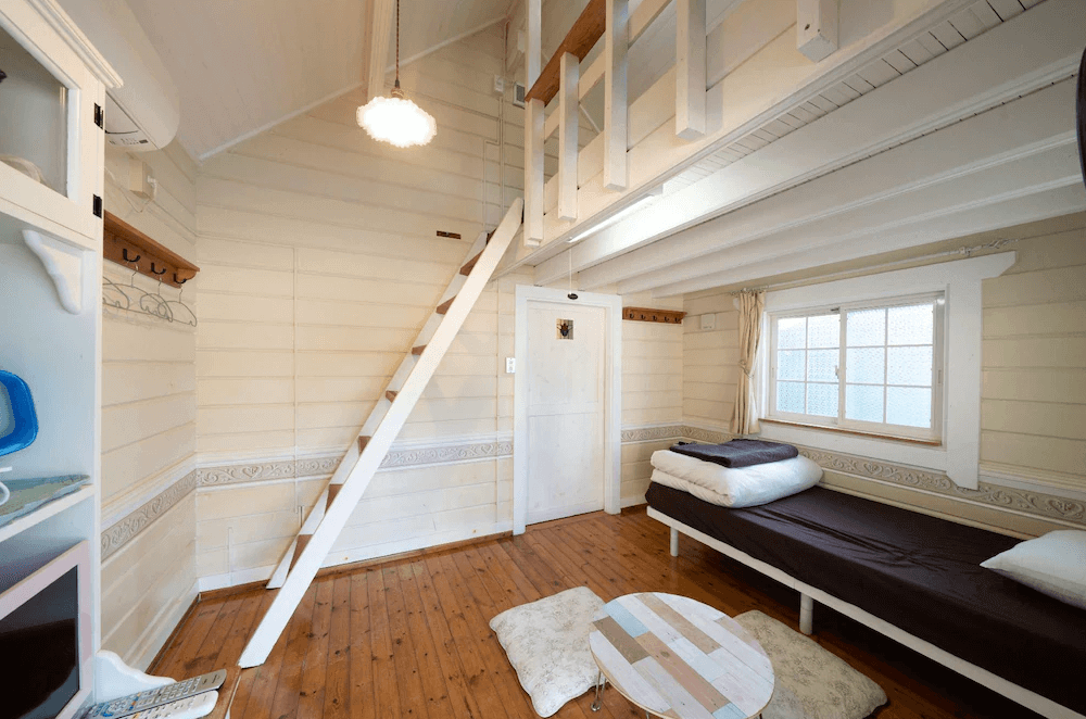 【屋久島住宿】「莫瑞諾考卡吉小屋（Cottage Morinokokage）帶有閣樓的可愛客房，設有單人床、木質地板與小茶几，下方空間溫暖舒適，上方可由樓梯通往的閣樓區。」