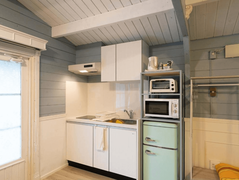 【屋久島住宿】「莫瑞諾考卡吉小屋（Cottage Morinokokage）的迷你廚房，配備冰箱、微波爐、烤箱與電熱水壺，藍白色調的小木屋風格令人放鬆自在。」