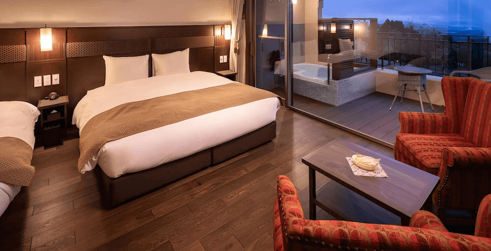 霧島山拉維斯塔飯店的豪華客房，室內擺設紅色古典扶手椅，陽台更設有私人露天浴池，讓房客能享受私密的泡湯時光並欣賞戶外景色。