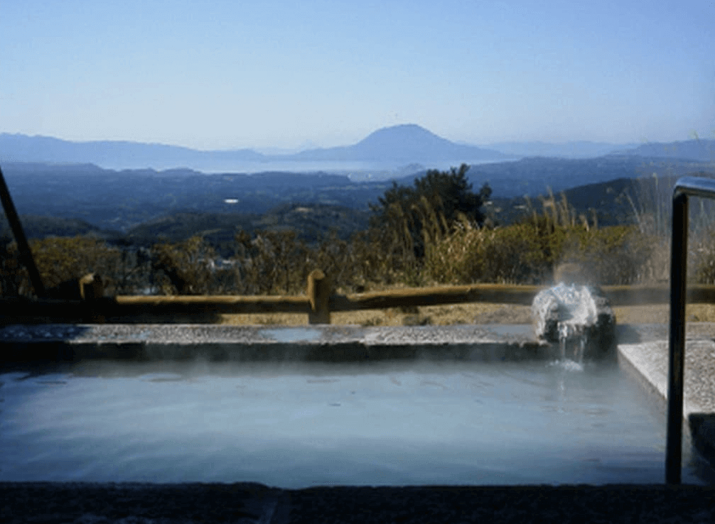 【霧島住宿】"霧島住宿精選示意圖"霧島溫泉旅人山莊飯店，擁有絕佳視野的露天溫泉浴池，溫泉水氣氤氳，可遠眺壯麗的櫻島火山與連綿山景。