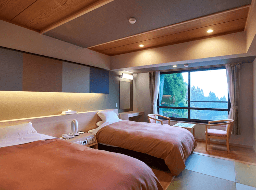 【霧島住宿】霧島酒店的西式雙床客房，設計簡約明亮，房內設有大片觀景窗，讓房客在舒適的休息空間中也能飽覽窗外茂密的森林景致。
