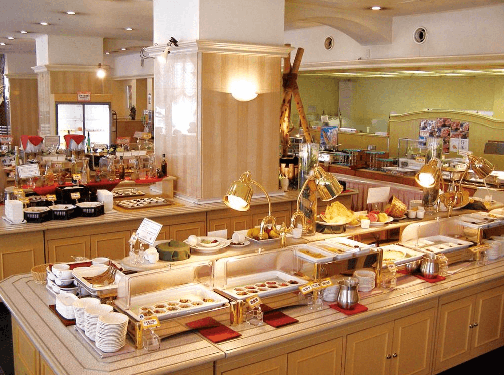 【鹿兒島住宿】鹿兒島陽光皇家飯店 (Kagoshima Sun Royal Hotel) 的自助餐廳區域，空間寬敞明亮，設有豐富的料理取餐檯與金色保溫燈設備，提供多樣化的餐飲選擇。
