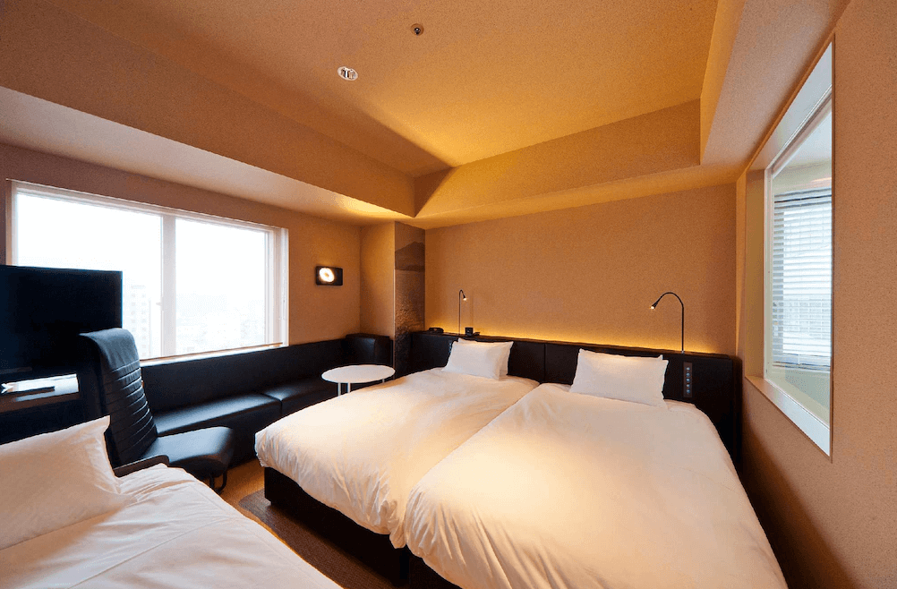【鹿兒島住宿】鹿兒島雷姆飯店 (Remm Kagoshima) 的雙床客房，設計簡約時尚，房內配備品牌專屬的高級按摩椅與靠窗長型黑色沙發區，致力於為旅客打造最舒適的助眠休憩空間。