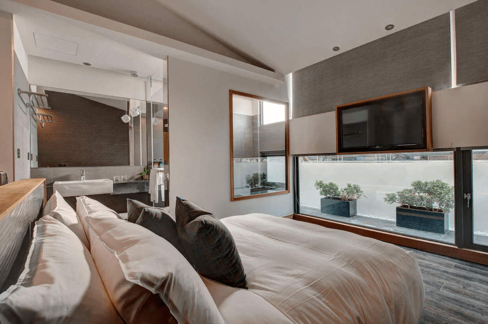 EG Hostel景觀雙人房，房內擁有低檯度的大面玻璃窗，可欣賞戶外陽台的綠植造景，採光極佳，配有壁掛電視與舒適大床，設計簡約現代且具穿透感。