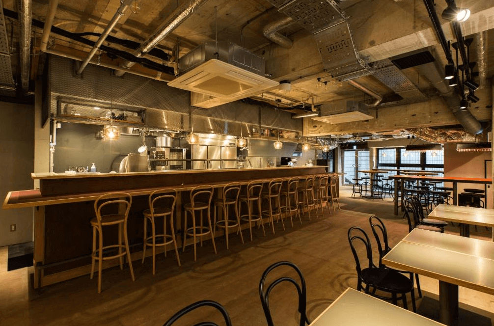 UNPLAN Shinjuku 的地下一樓酒吧餐廳,裝潢充滿粗獷的工業風格,天花板管線外露搭配溫暖燈光,設有長條吧台與多組座位,是旅人交流與小酌的熱鬧據點。