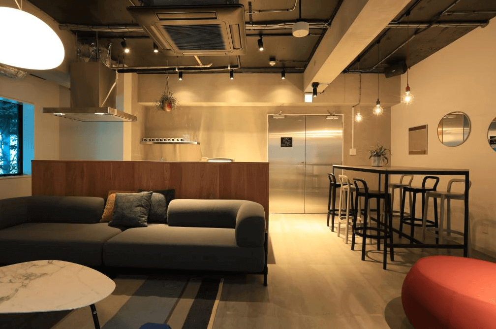 UNPLAN Shinjuku 的公共交誼廳與共用廚房,空間寬敞並設有舒適的L型沙發休憩區,配備現代化的不鏽鋼中島廚房,營造出如家般自在的社群生活氛圍。