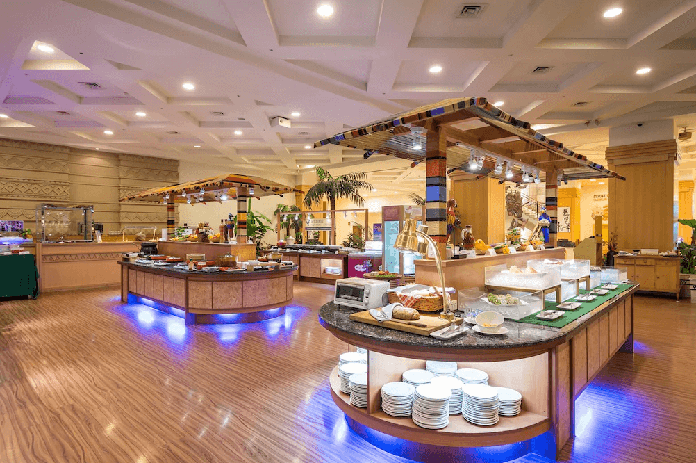 【台東寵物友善住宿】娜路彎大酒店 (Naruwan Hotel) 的自助百匯餐廳，取餐檯設計融入濃厚的原住民茅草屋風格，空間寬敞挑高，燈光溫馨明亮，提供旅客在充滿在地特色的氛圍中享用豐富美食。