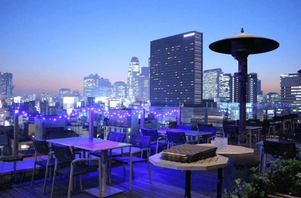 新宿格蘭貝爾飯店著名的頂樓高空酒吧(Roof Top Bar & Terrace),露天座位區在夜間點亮夢幻的藍紫色氛圍燈,旅客可在此一邊小酌,一邊近距離眺望新宿摩天大樓群的璀璨天際線。