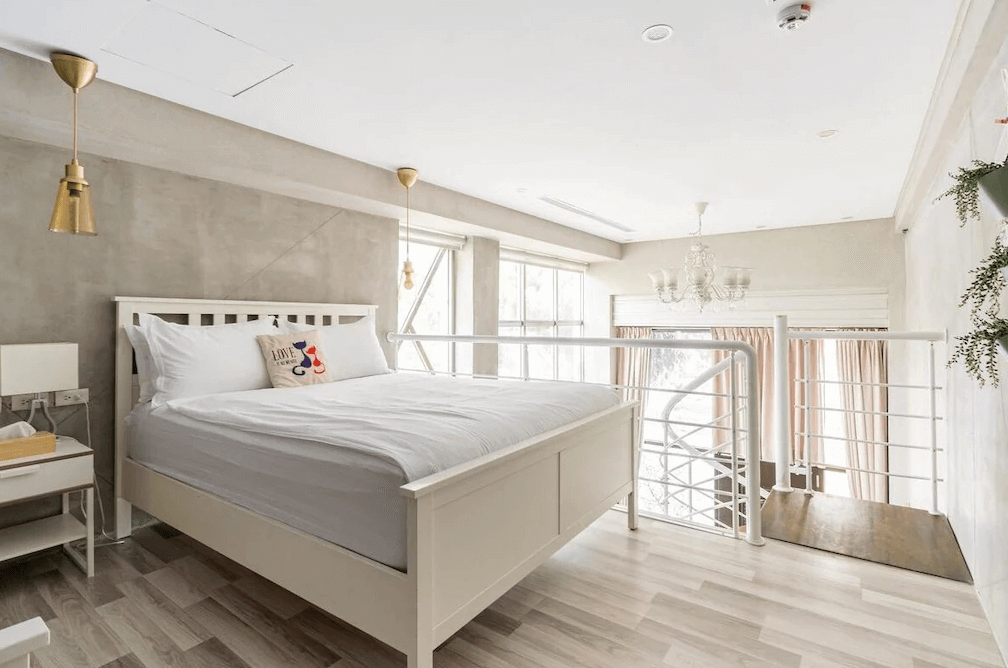 智旅南投體驗館樓中樓房型（閣樓睡眠區），位於二樓的臥室空間採光極佳，懸掛著精緻的白色吊燈，透過白色欄杆可俯瞰下方客廳，營造出夢幻的Loft度假氛圍。