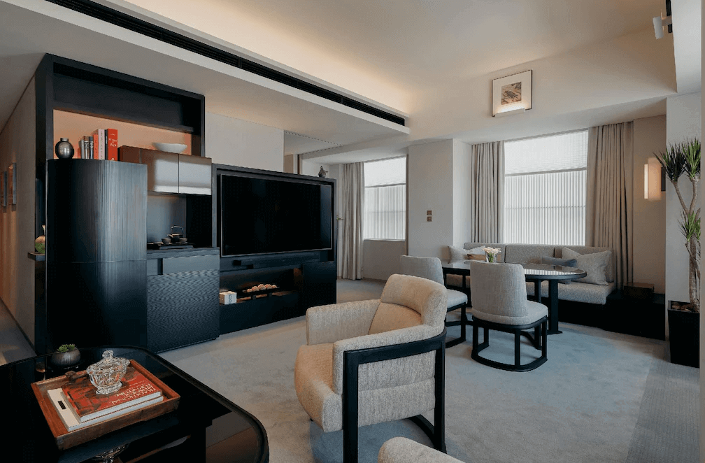 東京柏悅飯店的套房起居室,空間配置極為寬敞,設有獨立的沙發休憩區與圓形餐桌,搭配極簡的現代藝術掛畫,展現如豪宅般的居家奢華感。