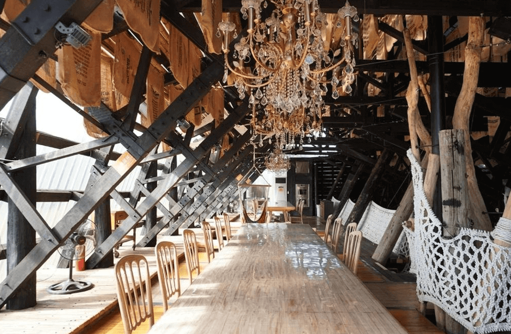 橘舍三食 (Orange Forest) 的半開放式景觀餐廳「山里廚房」，保留了粗獷的黑色鋼骨結構，天花板懸掛著多盞華麗的水晶吊燈與裝飾用的麻布袋，搭配長條原木餐桌，營造出原始工業風與奢華感撞擊的獨特用餐氛圍。