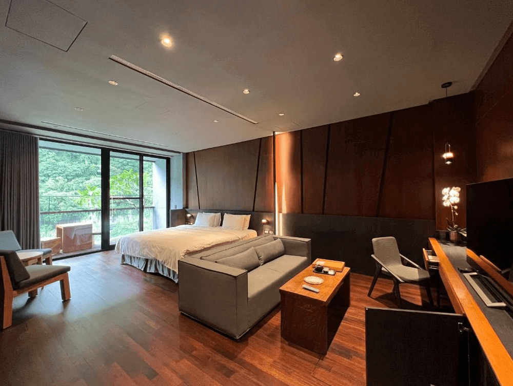 【苗栗寵物友善住宿】泰安觀止溫泉會館 (Onsen Papawaqa) 的觀止套房，室內採用大量的肖楠木與深色木質裝潢，散發著淡雅木香，寬敞的起居空間配有灰色沙發與落地窗，將泰安山區的綠意完美引入室內。