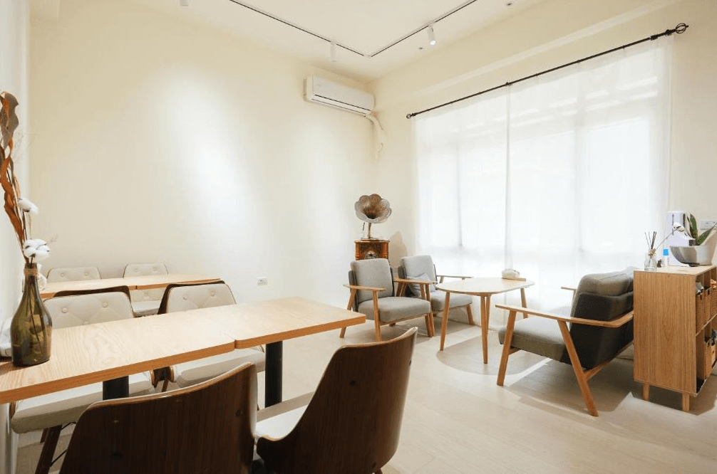 【台東寵物友善住宿】米璐民宿 (Milu B&B) 的公共交誼廳與用餐空間，擁有大面積的採光窗與透光白紗簾，擺設溫潤的木質桌椅與復古留聲機，搭配乾燥花藝裝飾，是個充滿文青氣息的休憩角落。