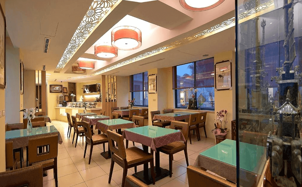 芝柏山汽車旅館中西式餐廳，用餐環境明亮典雅，天花板飾有精緻雕花燈箱，座位區寬敞舒適，提供住客自助式早餐，旁有玻璃展示櫃陳列藝術品。
