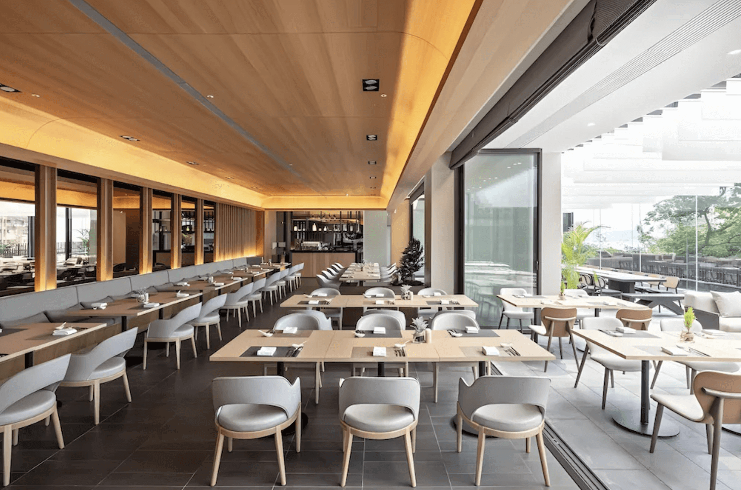 蘊泉庄溫泉飯店餐廳用餐環境，天花板採用溫潤的木質弧形設計，搭配大片落地玻璃門將戶外光線與綠意引入室內，氛圍明亮且充滿禪意。
